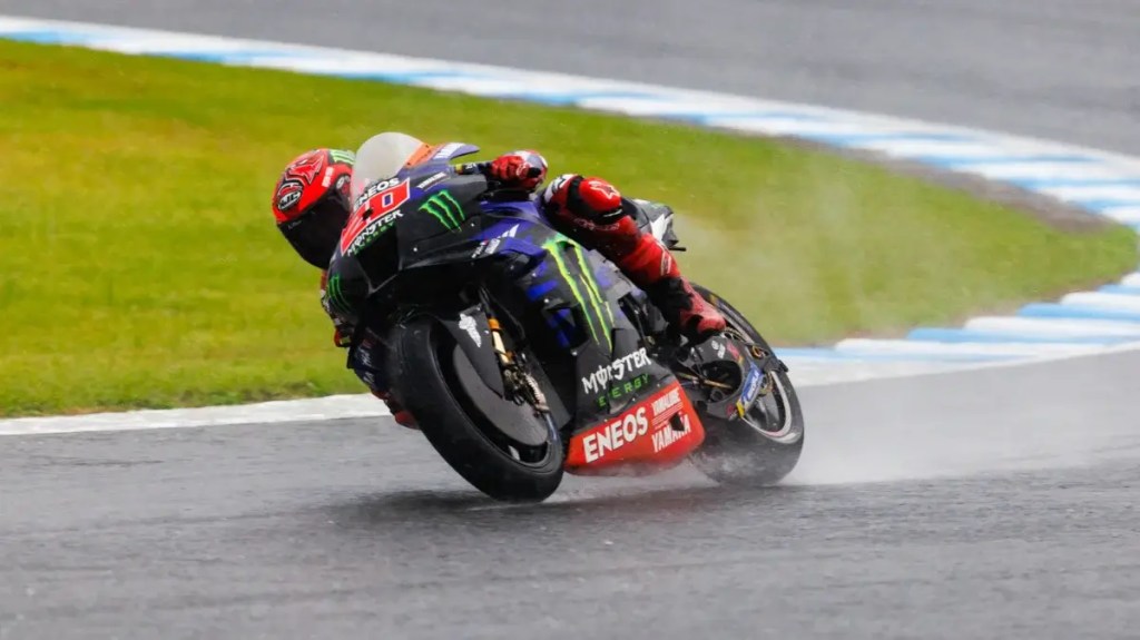 Motociclista compitiendo en una pista húmeda durante una carrera de MotoGP.