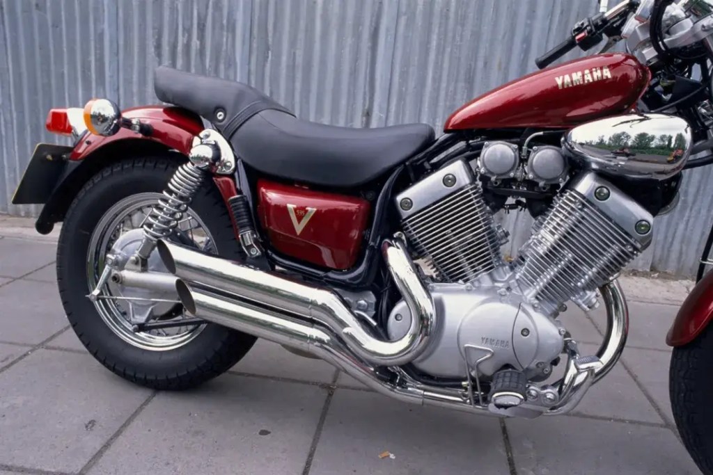 Close-up view of a red Yamaha Virago 535 motorcycle, showcasing its V-twin engine, chrome exhaust pipes, and sleek design elements.