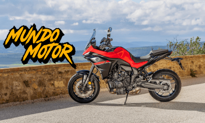 Vista lateral de la Yamaha Tracer 7 2025 en color rojo con paisaje rural al fondo