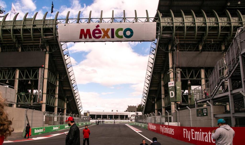 Vista del Autódromo Hermanos Rodríguez en Ciudad de México, con una gran lona que dice 'MÉXICO' en la entrada al circuito.