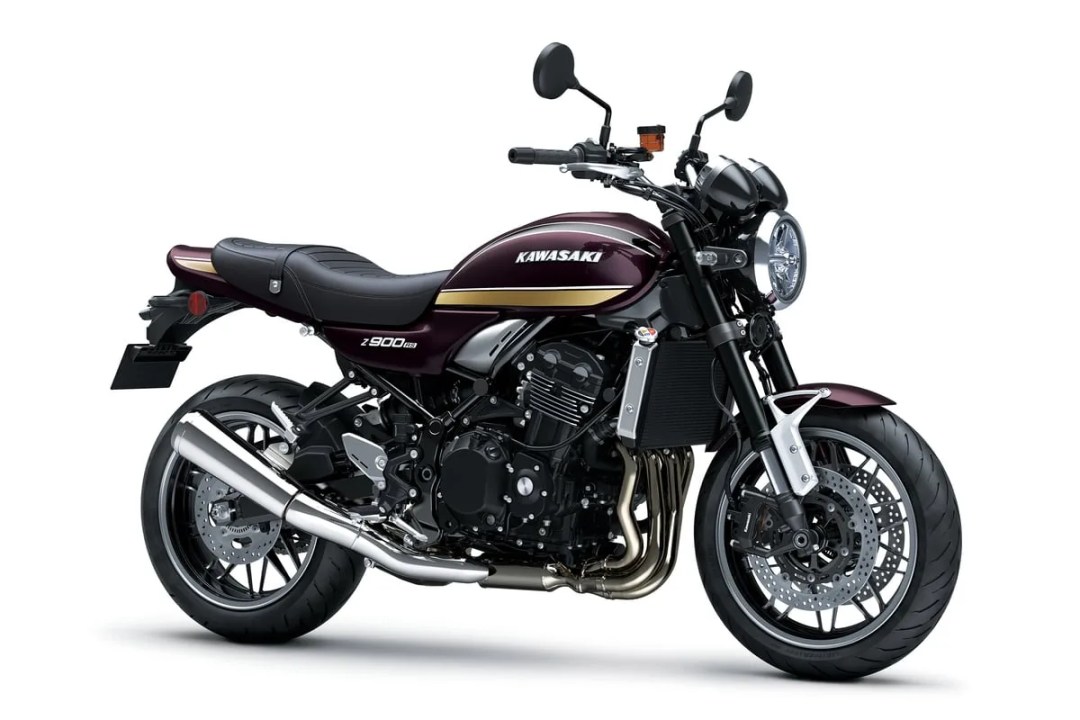 Motocicleta Kawasaki Z900RS 2026 de color burdeos con diseño retro, destacando su motor bicilíndrico y detalles modernos como el sistema de asistencia basado en IMU y el acelerador electrónico.