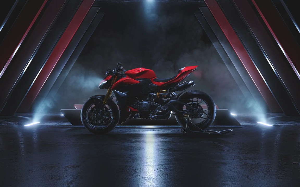 La nueva Ducati Hypermotard V2 2026 en un entorno oscuro, iluminada por luces dramáticas y reflejos, destacando su diseño deportivo y moderno.