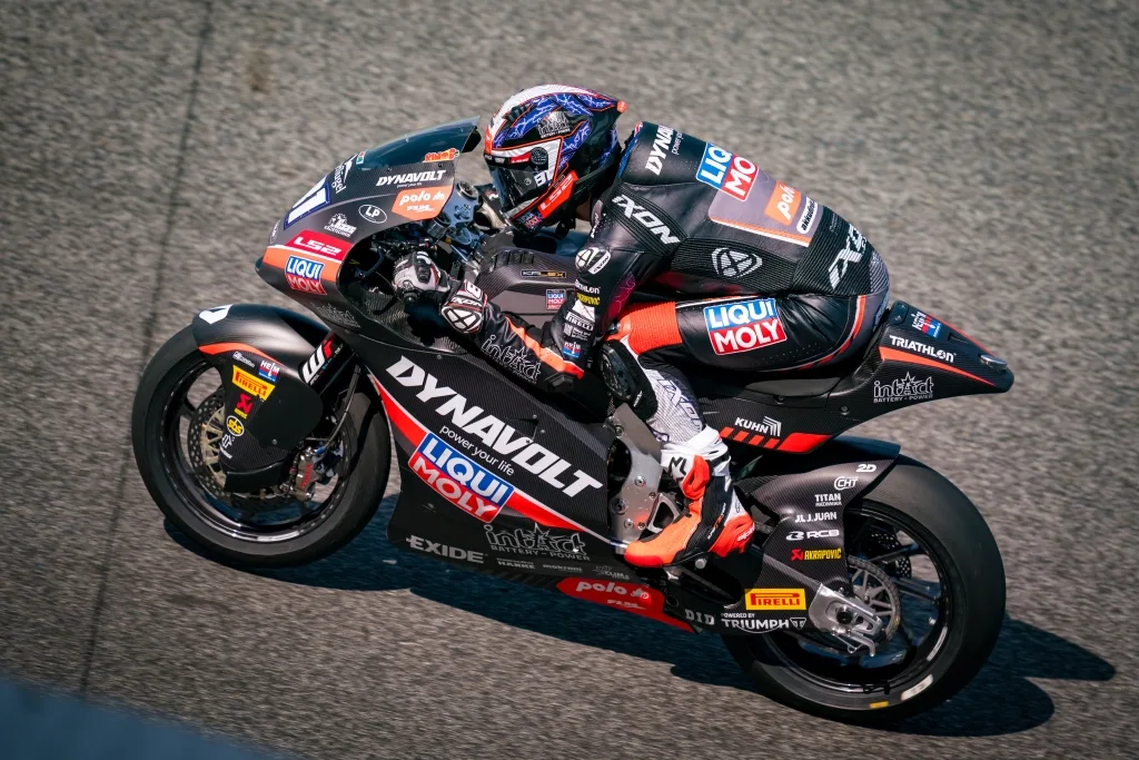 Piloto de Moto2 en acción sobre su moto del equipo LIQUI MOLY Dynavolt Intact GP, mostrando velocidad en una pista.