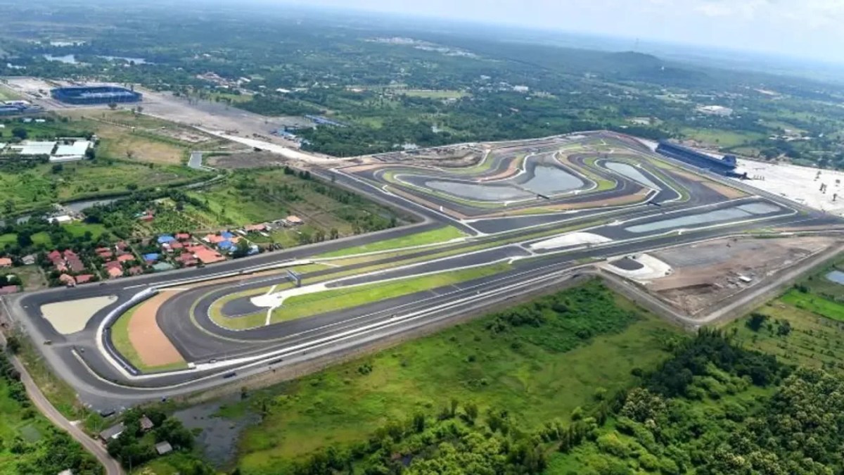 Aerial view of a racing circuit surrounded by green fields and residential areas.