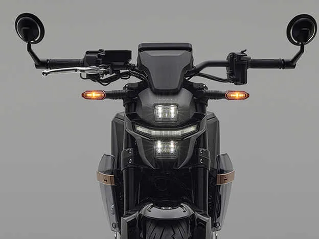 Vista frontal de una motocicleta negra con luces LED y manillares.