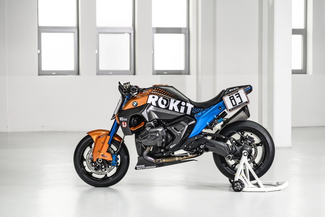 A BMW motorcycle design featuring a striking color combination of orange, blue, and black, displayed on a white background with natural light illuminating the scene.